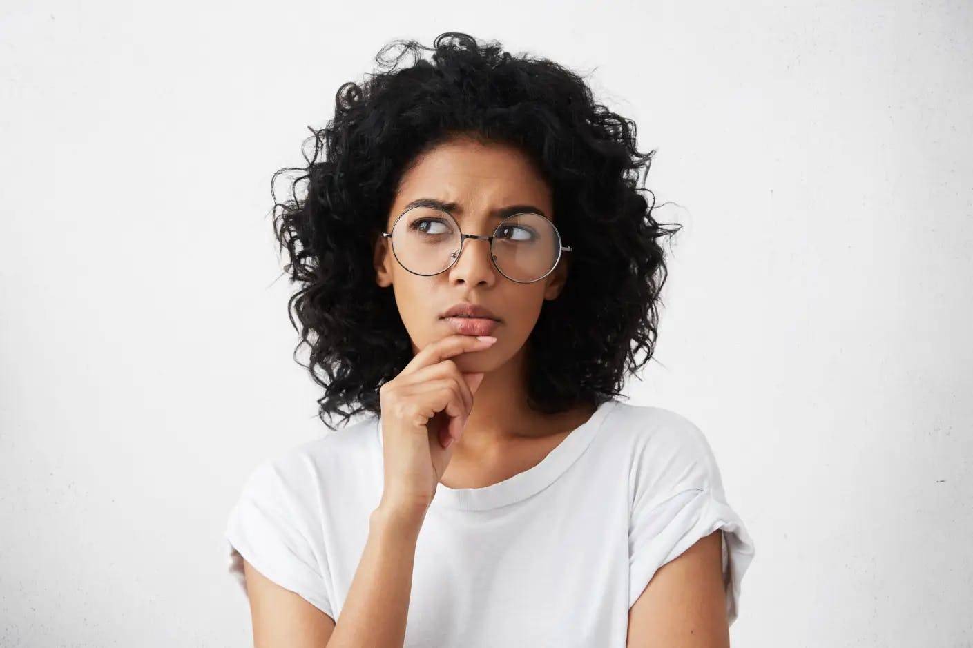 Une femme de couleur à lunettes se demande quand elle doit commencer ses séances d'épilation définitive.